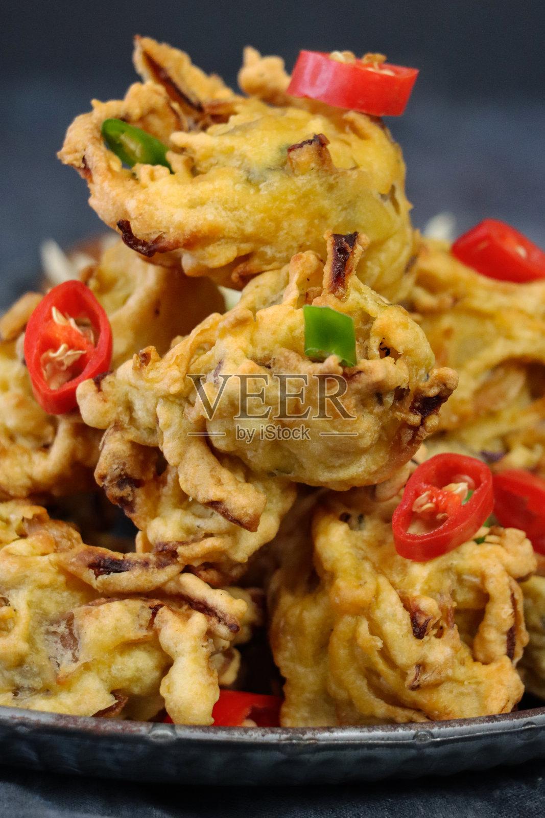 整幅图片是一堆自制的酥脆洋葱，配以切碎的红绿辣椒，做成有图案的菜肴，印度菜素食小吃，灰色背景，重点放在前景照片摄影图片