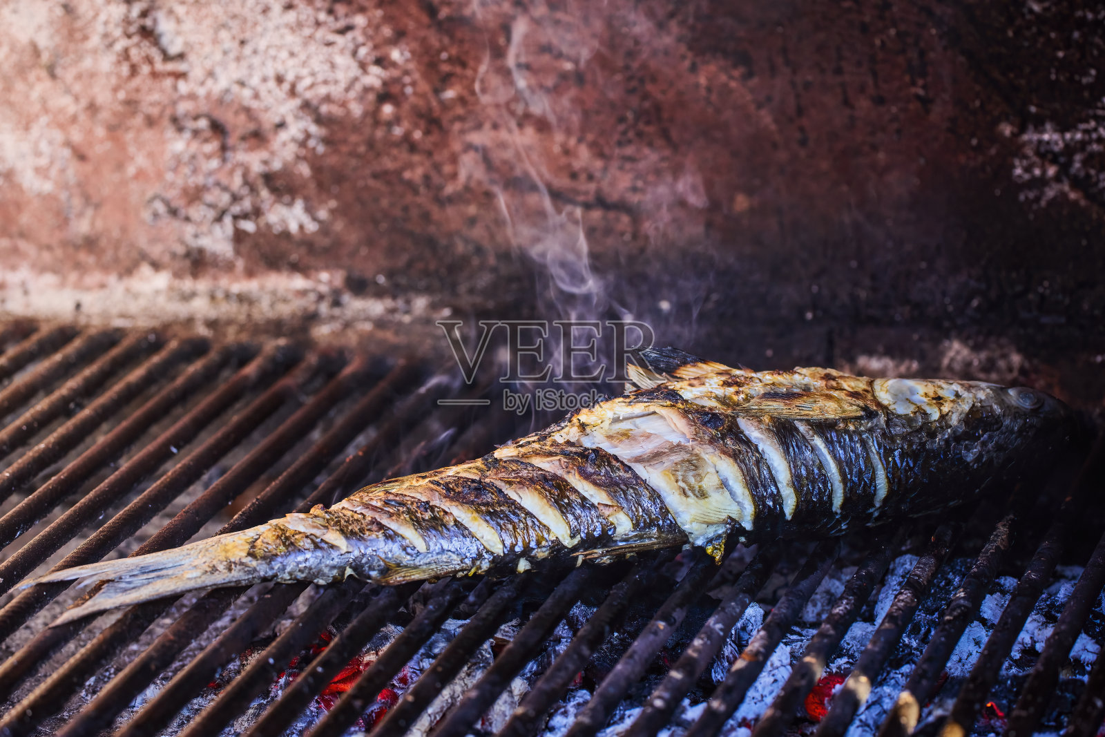 在烤架上接近整条鱼。照片摄影图片