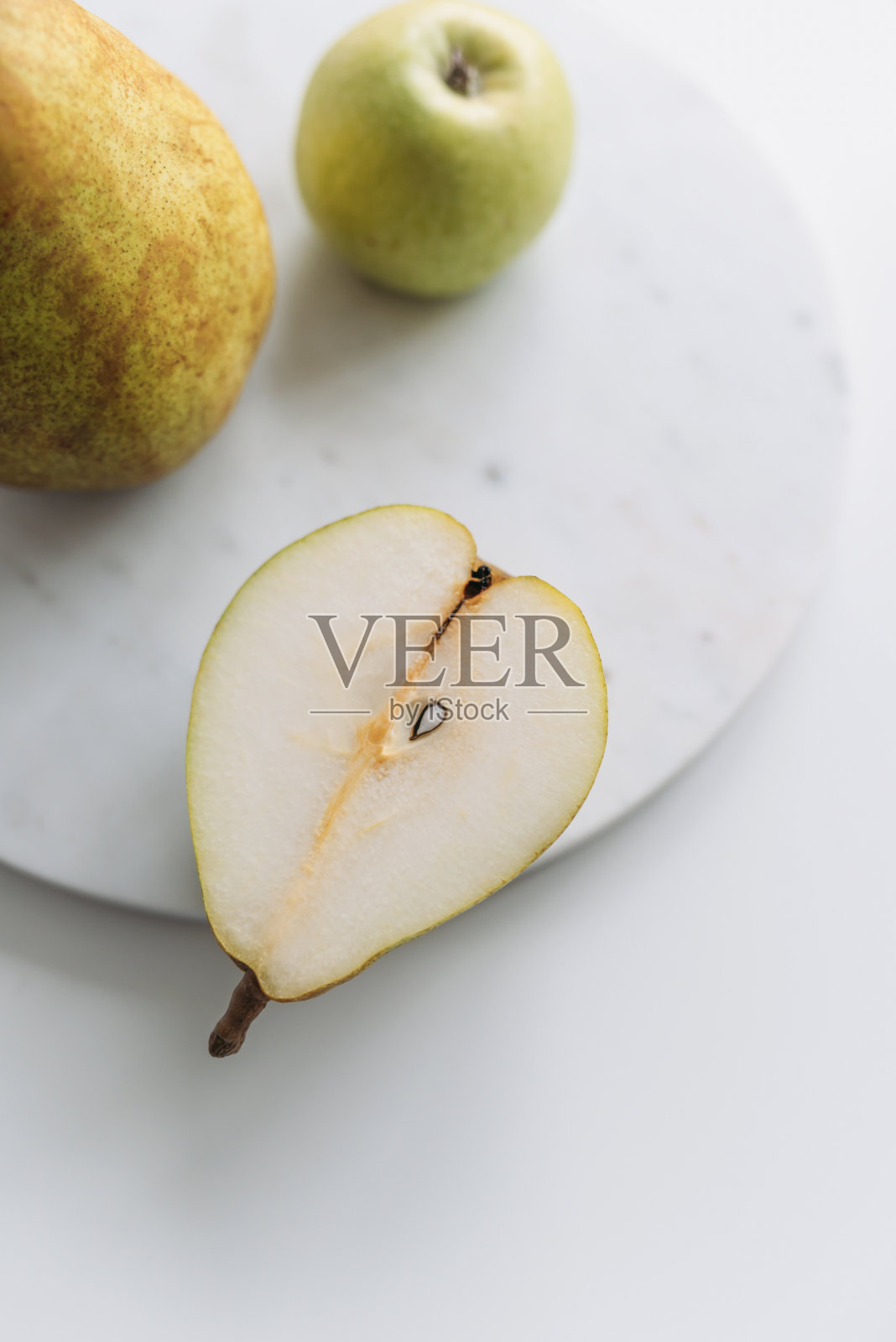 梨子和苹果在白色的大理石桌子上。近距离照片摄影图片