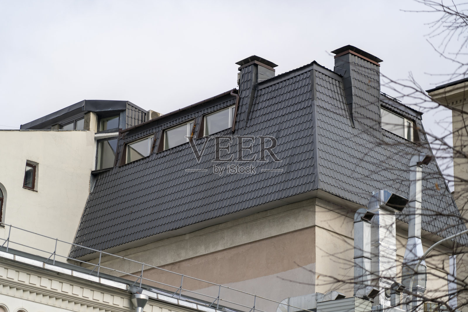 带有窗户的住宅建筑的斜屋顶，有金属涂层。屋顶与排水沟，斜坡，雨水管和排水沟，潮汐和天窗对抗天空照片摄影图片