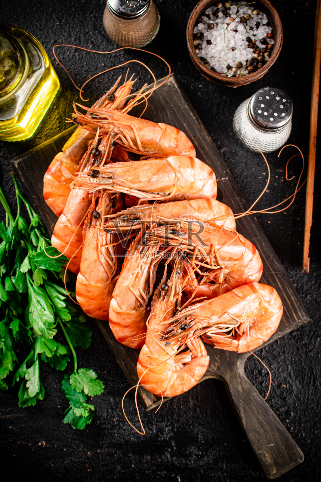 用香菜和香料在切菜板上煮虾。照片摄影图片