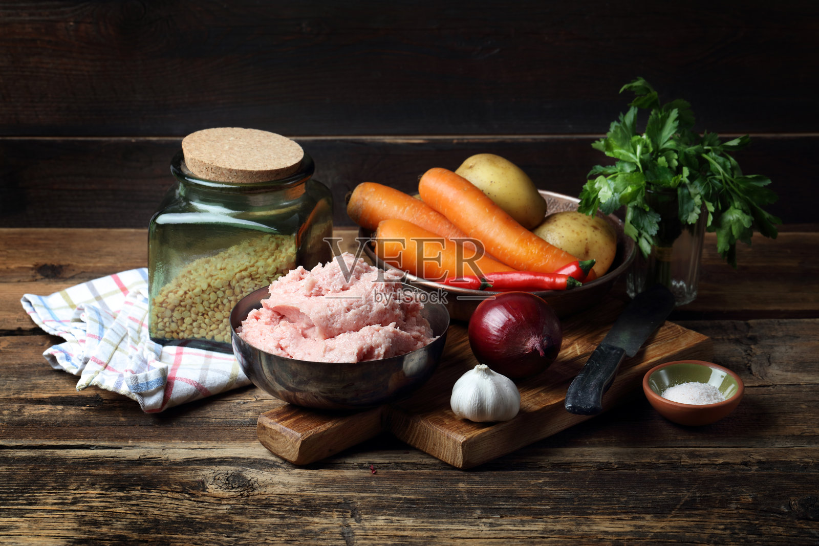 木桌上放着生肉末、土豆、胡萝卜、洋葱、大蒜、欧芹、辣椒、盐和切碎的豌豆照片摄影图片