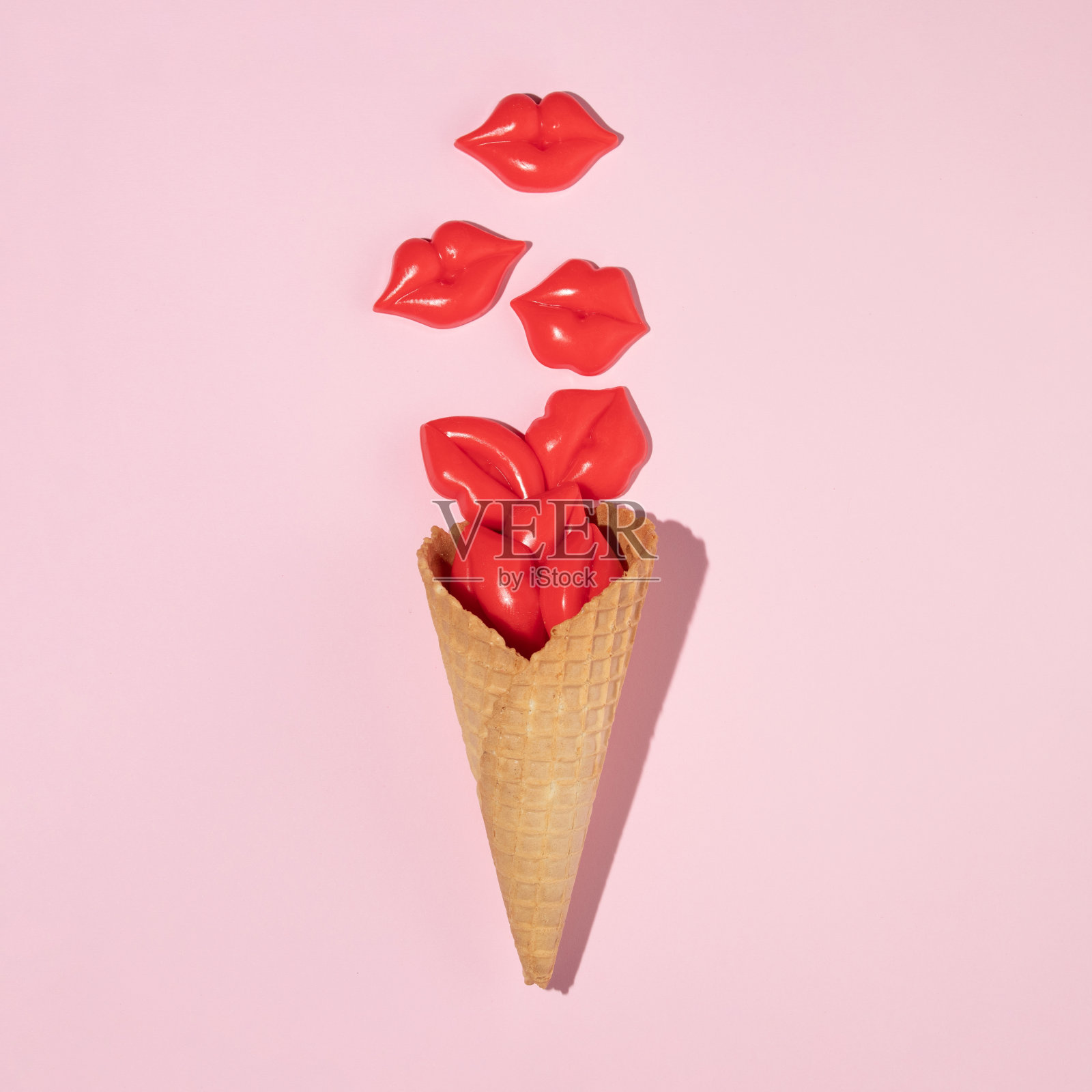 甜筒冰淇淋与明亮的红色嘴唇雕像在柔和的粉红色背景。最小的夏季创意概念。创造性的食物的想法。平的。照片摄影图片