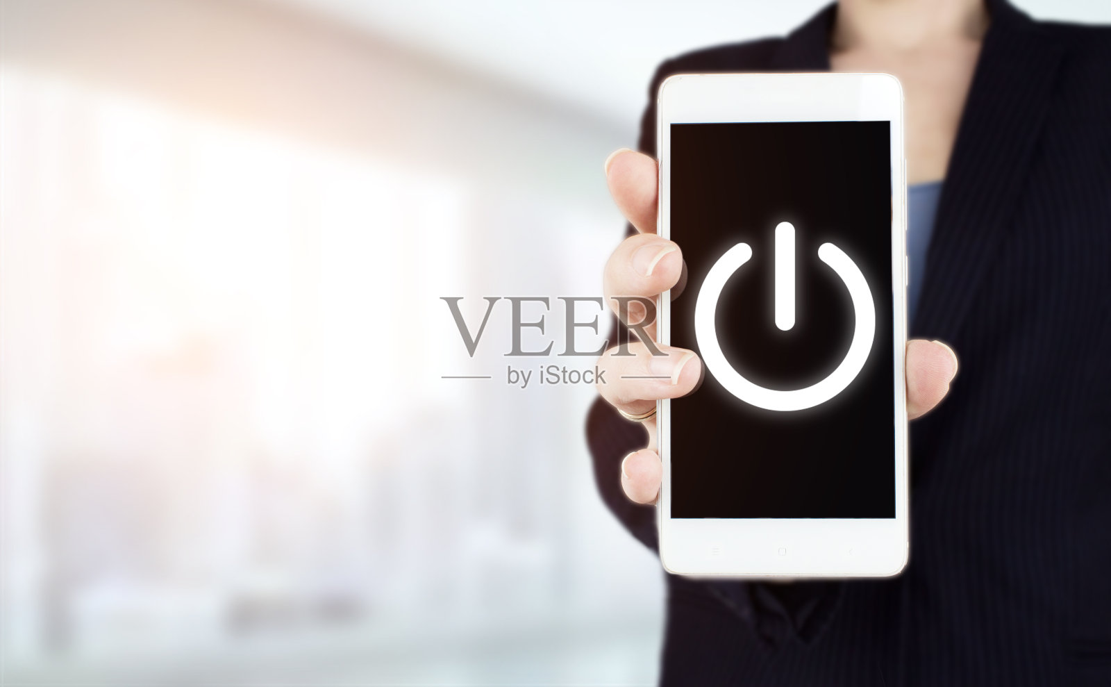 启动经营理念。启动的概念。手持白色智能手机与数字全息图按下按钮的虚拟屏幕标志上的灯光模糊的背景。照片摄影图片