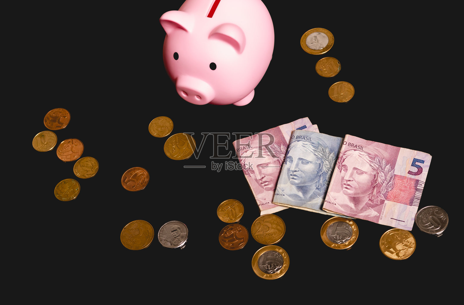 黑色的桌子上放着一个装满巴西雷亚尔纸币和硬币的储钱罐。从以上观点。巴西经济、金融和投资。照片摄影图片