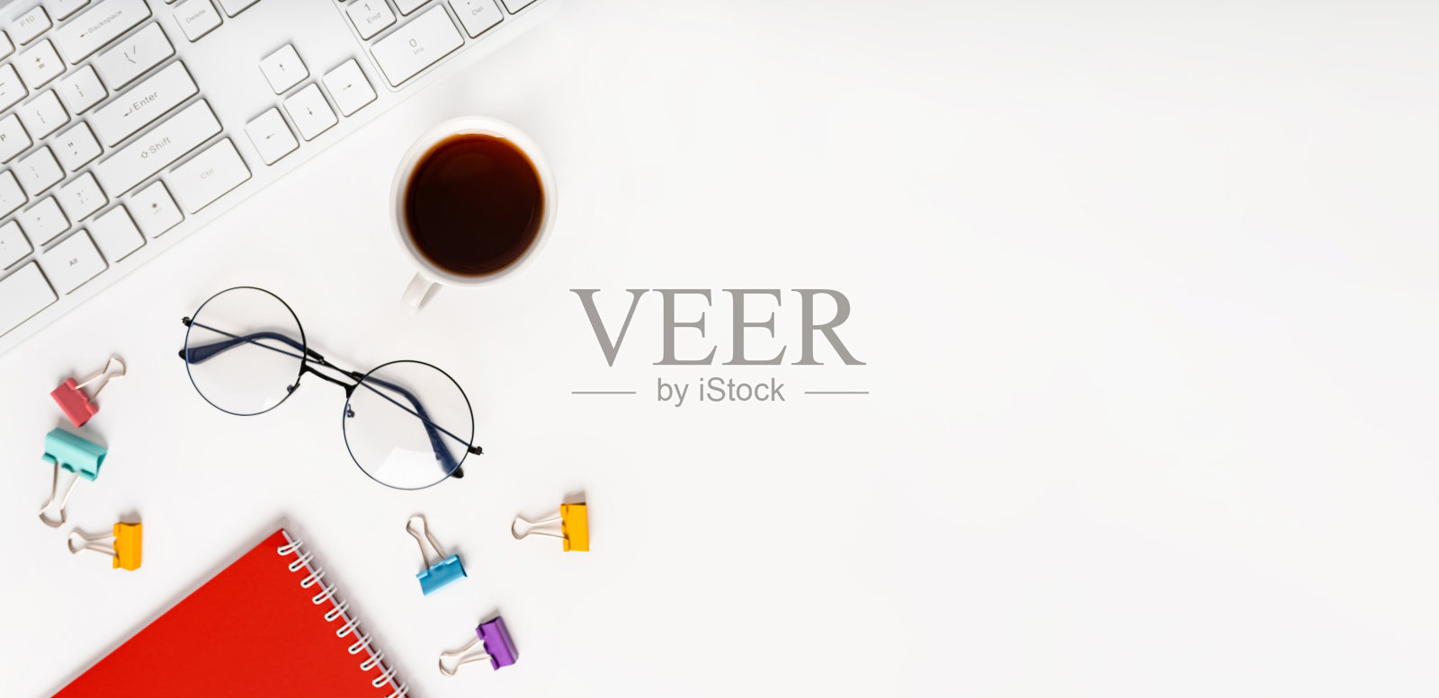 俯视图的现代办公桌，笔记本，眼镜，键盘和咖啡或茶杯，白色背景和文字的地方照片摄影图片