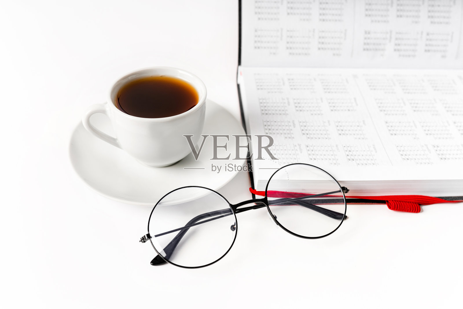 一个现代的办公桌，有一个记事本，眼镜和一个咖啡或茶杯，白色背景，有一个地方写文字照片摄影图片