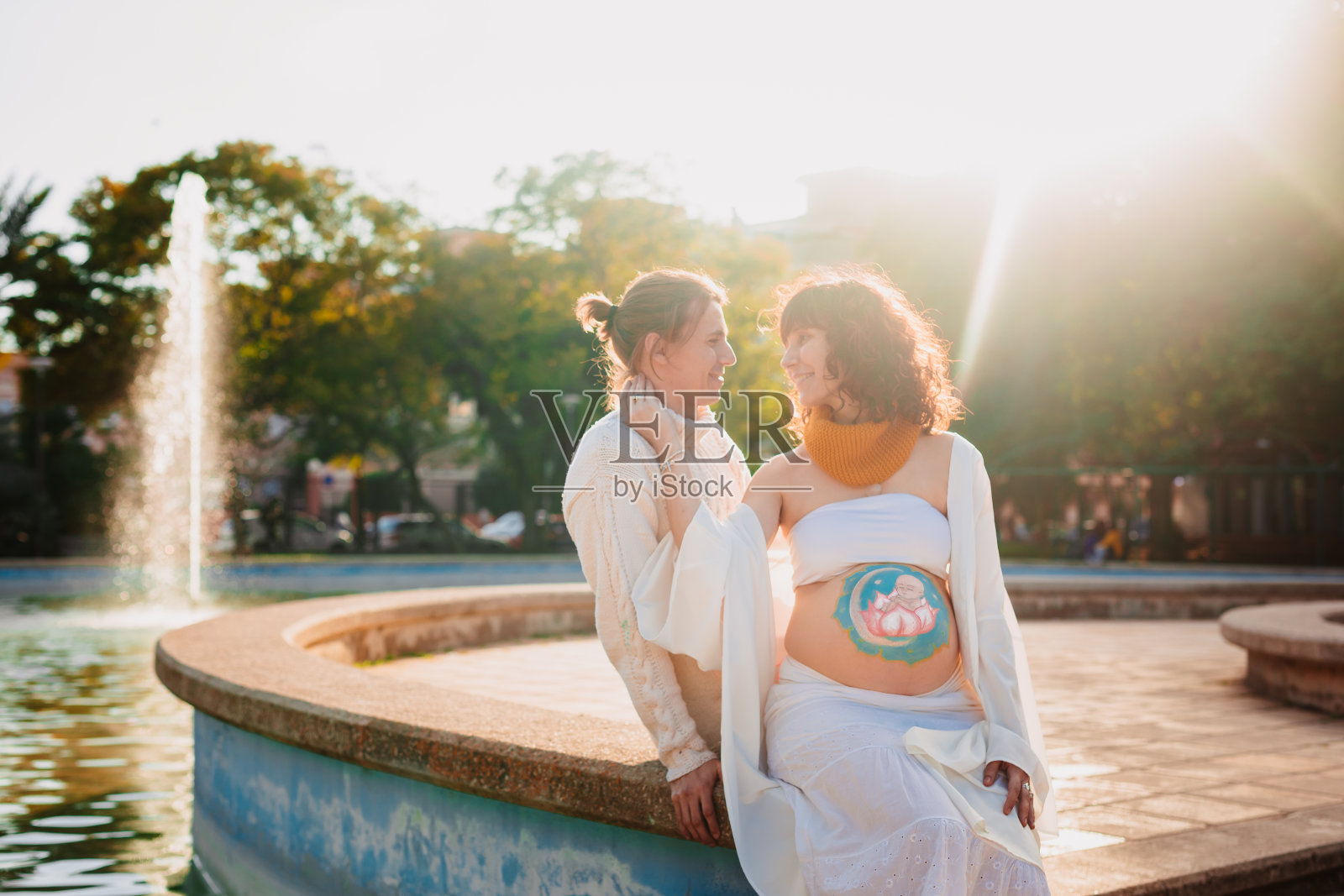 公园里腹部彩绘的孕妇与准爸爸照片摄影图片