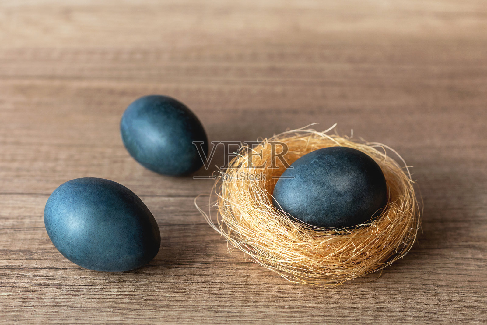 蓝色的复活节蛋在一个巢和木桌上照片摄影图片