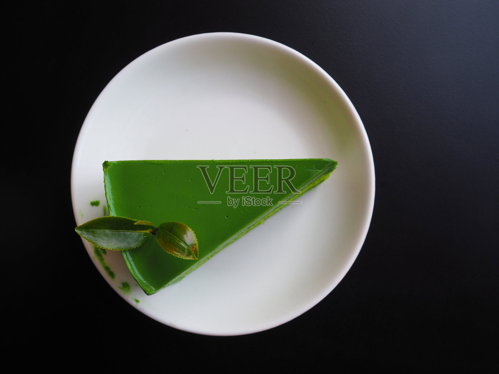 绿茶芝士蛋糕的俯视图在一个白色的盘子在黑色的背景照片摄影图片