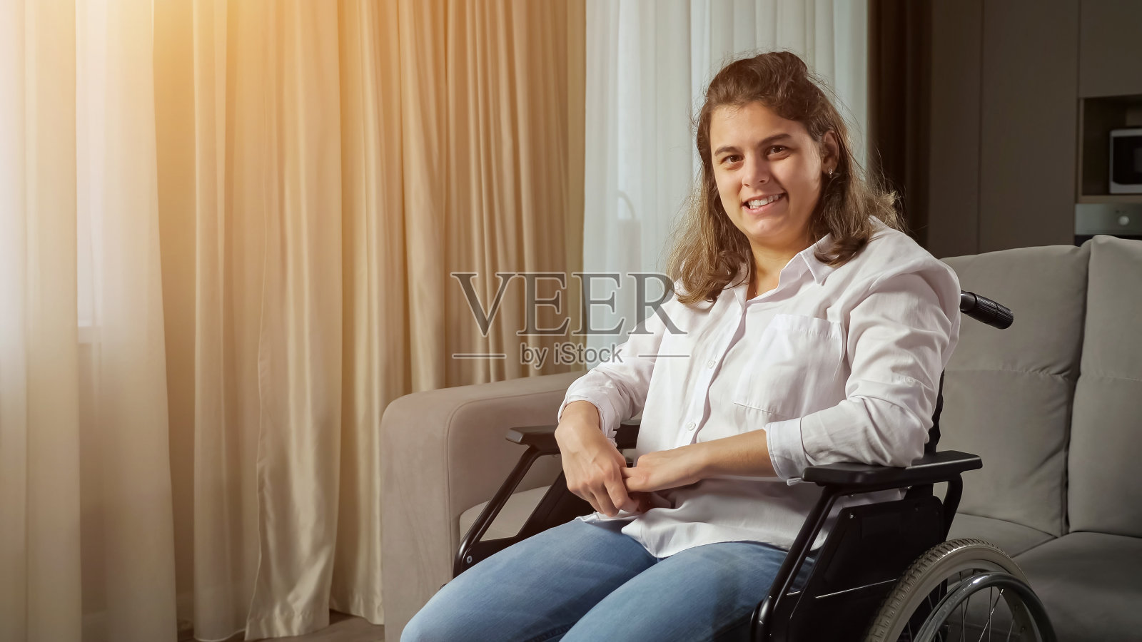 残疾妇女坐在沙发边的轮椅上微笑照片摄影图片