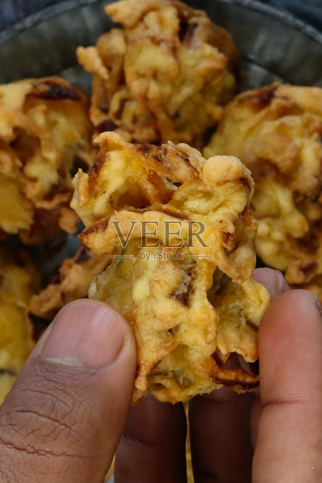 一个无法辨认的人从一盘又一盘的盘子里挑选酥脆的洋葱烤肉，印度街头小吃，灰色背景，高架视野照片摄影图片