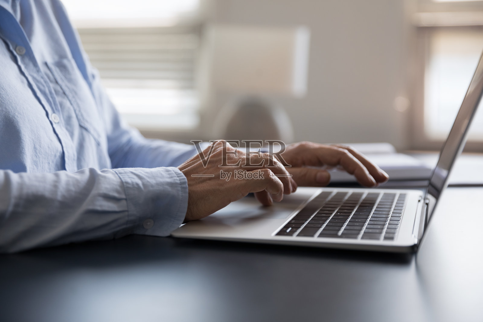 接近老年女商人在笔记本电脑键盘上打字。照片摄影图片