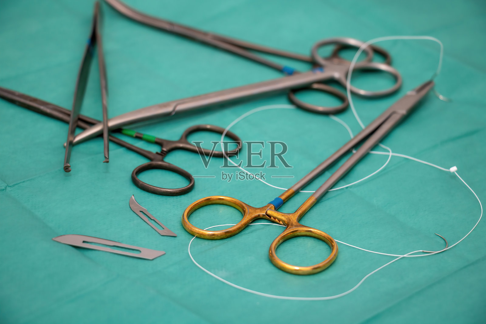 无菌手术器械，绿色织物背景。外科医生用不锈钢工具。照片摄影图片