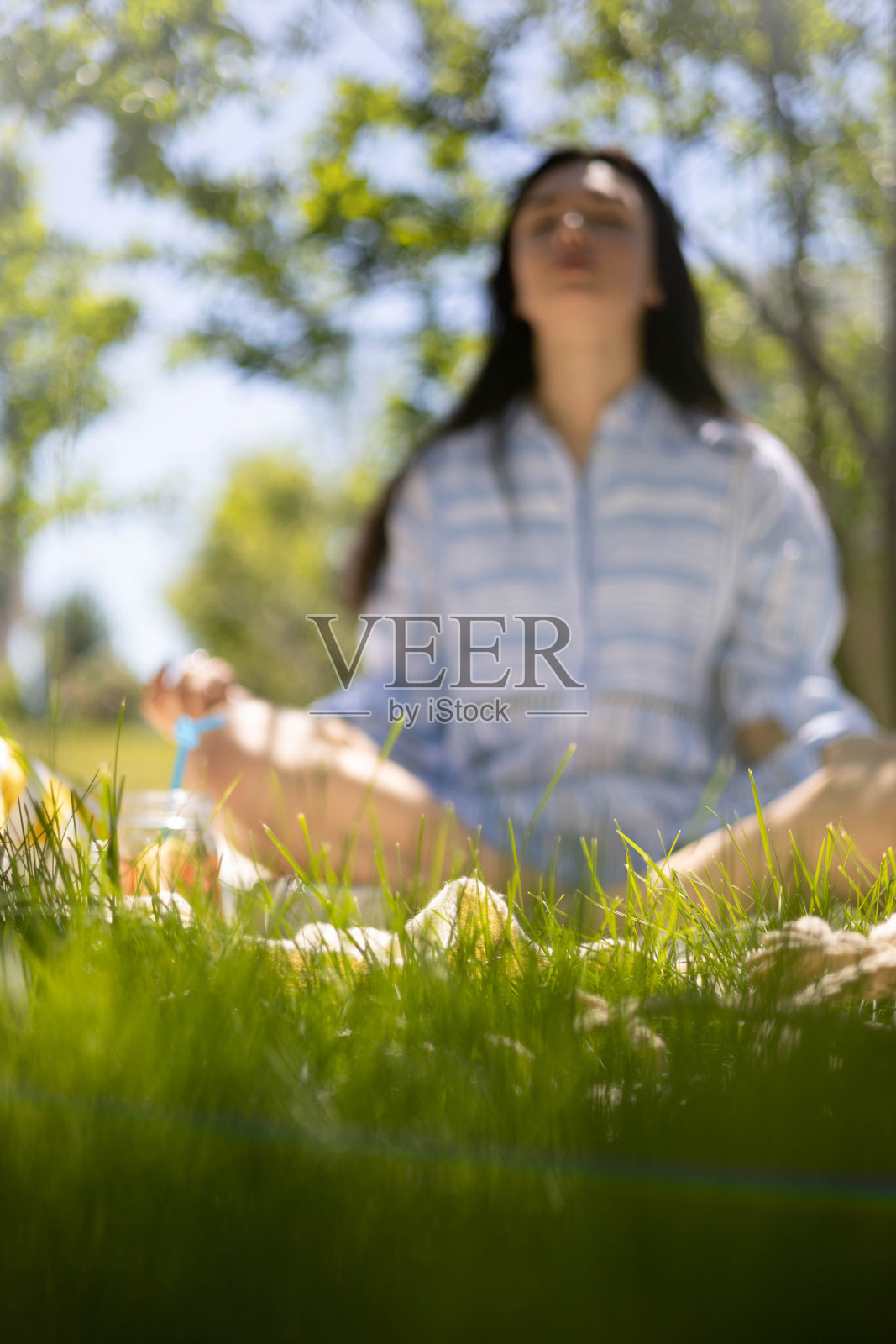 放松的女人坐在莲花的位置上格子享受早晨冥想在夏季花园公园照片摄影图片