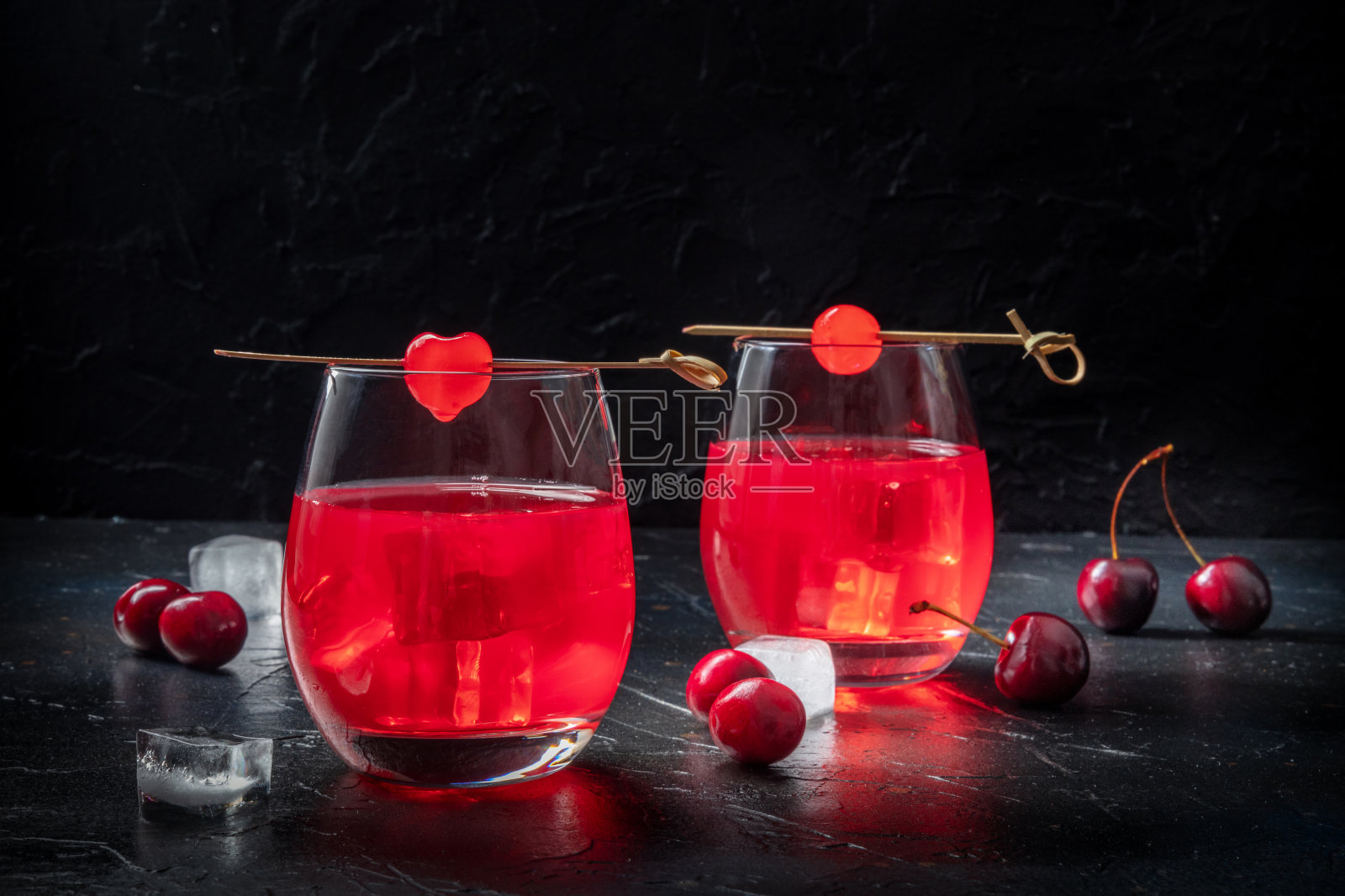 与樱桃鸡尾酒。酒精饮料在黑色背景上，加冰照片摄影图片