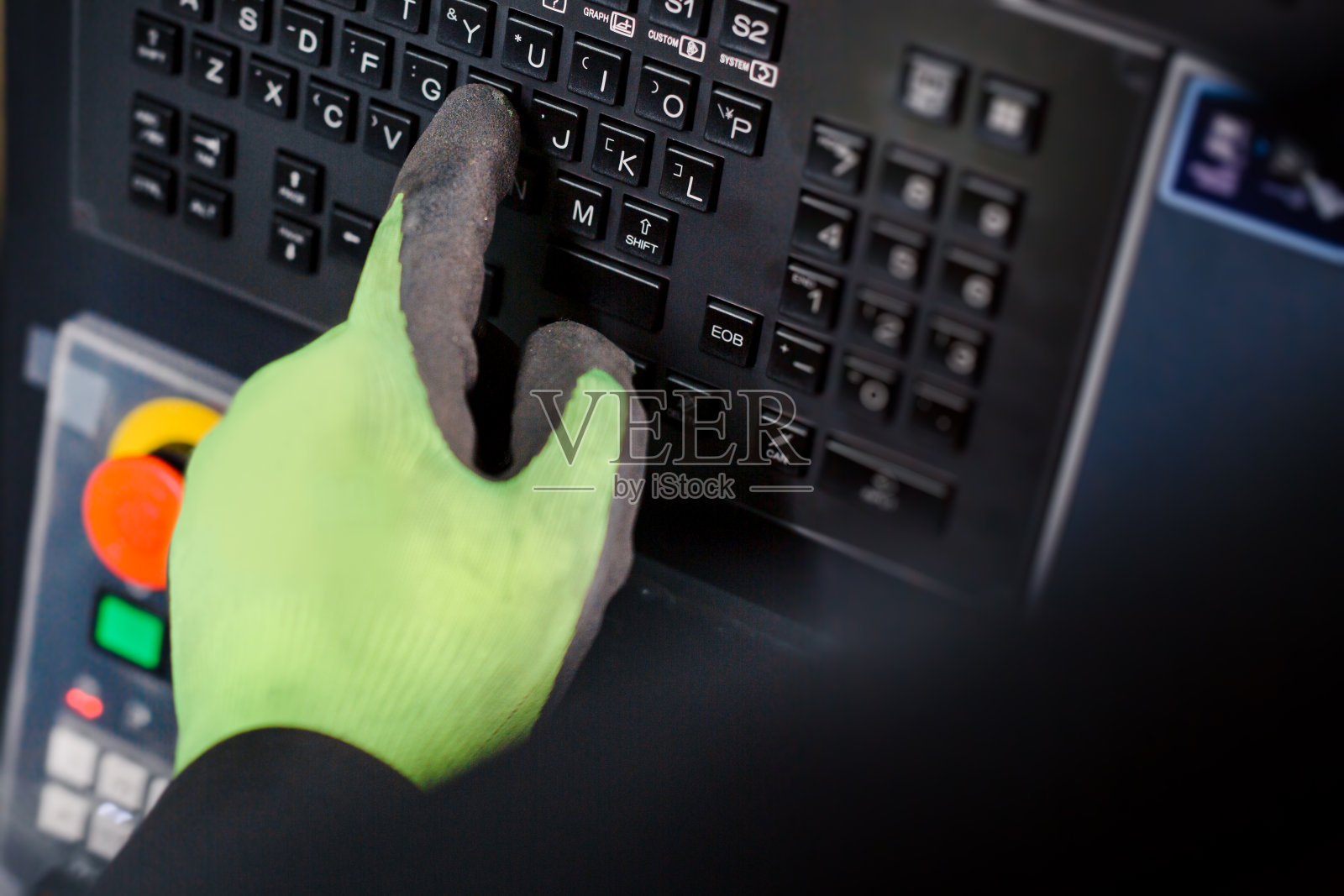 工业工人在工厂的数控机床上输入数据。照片摄影图片