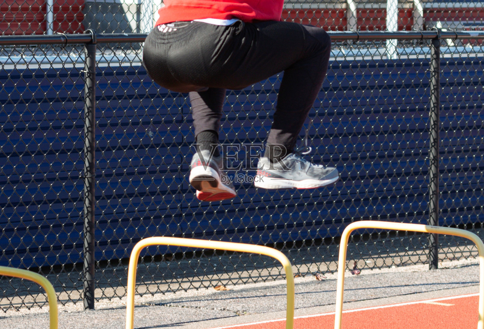 运动员越过跑道上的黄色栏杆照片摄影图片