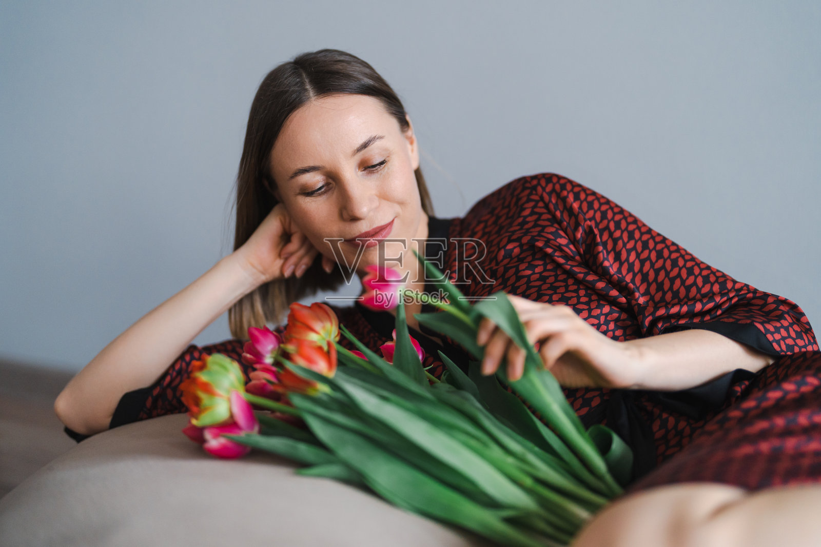 年轻女子喜欢在家放松地躺在柔软的豆袋上享受鲜花照片摄影图片