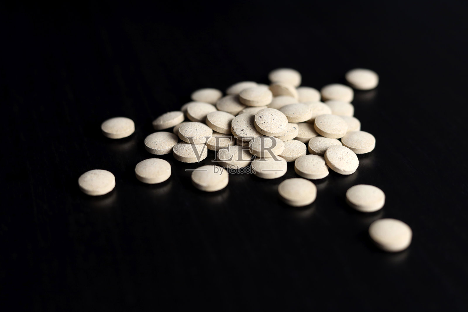 药丸散落在黑色的木桌上照片摄影图片