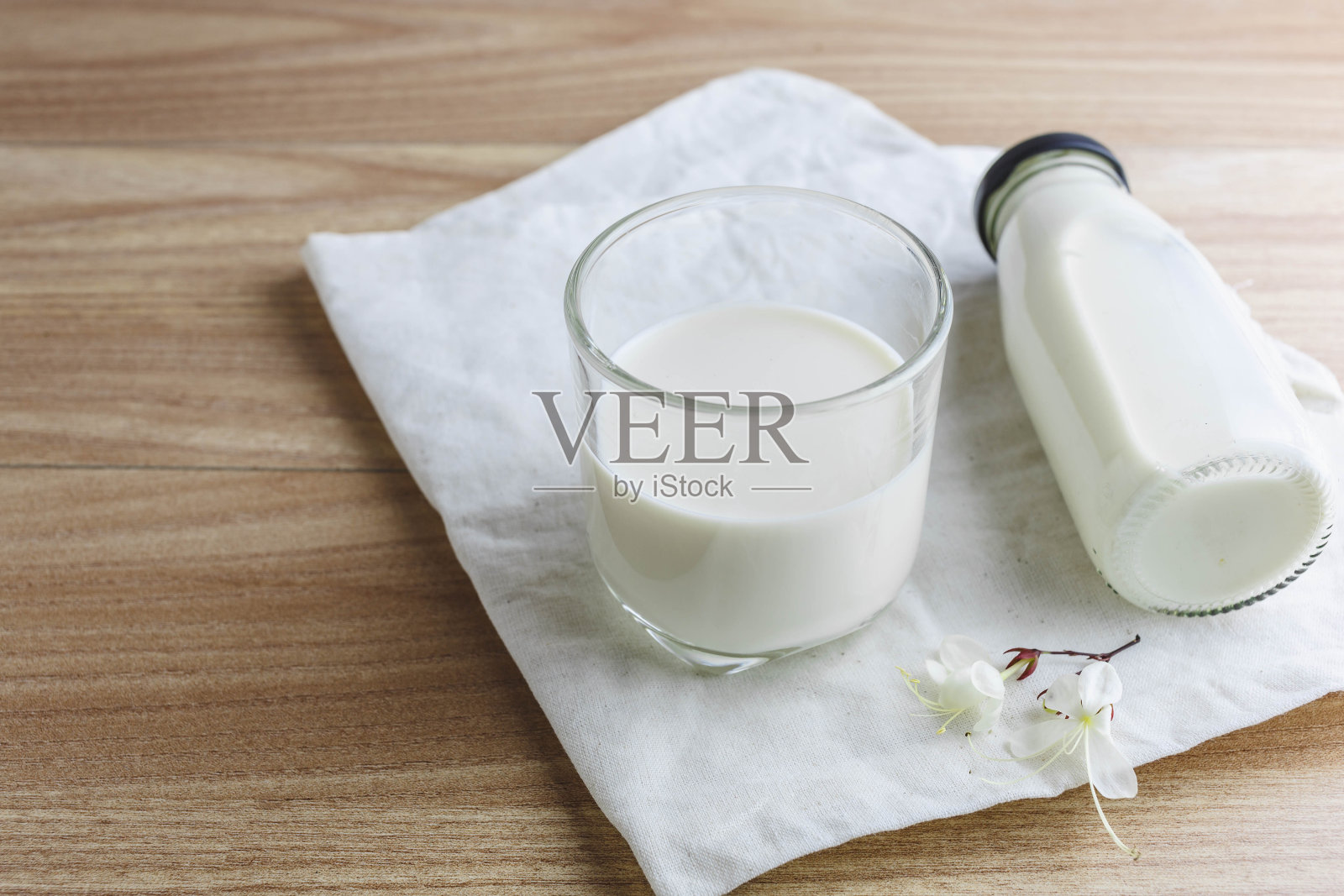 木桌上放着一瓶牛奶和一杯牛奶照片摄影图片