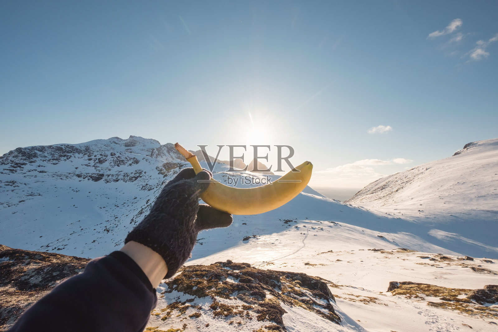 雪山之巅，旅行者手握熟透的黄香蕉照片摄影图片