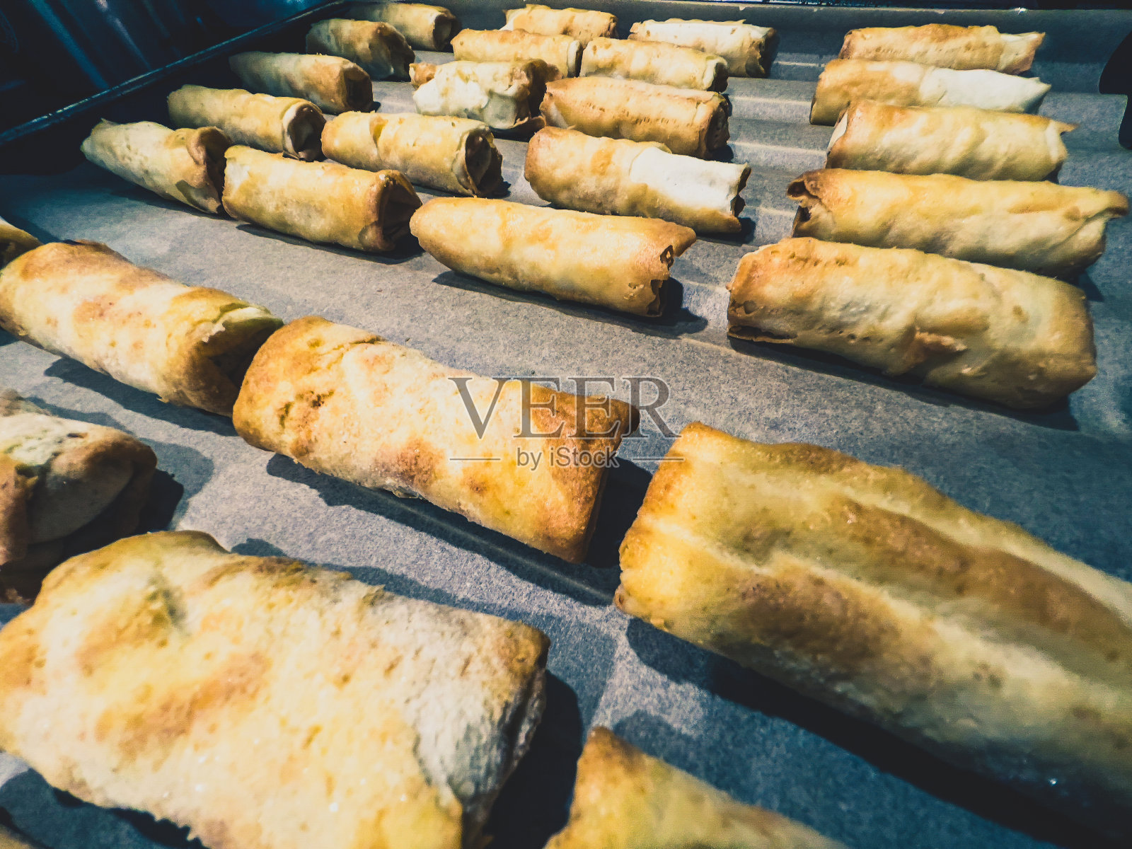 烤盘上的冰冻春卷。照片摄影图片