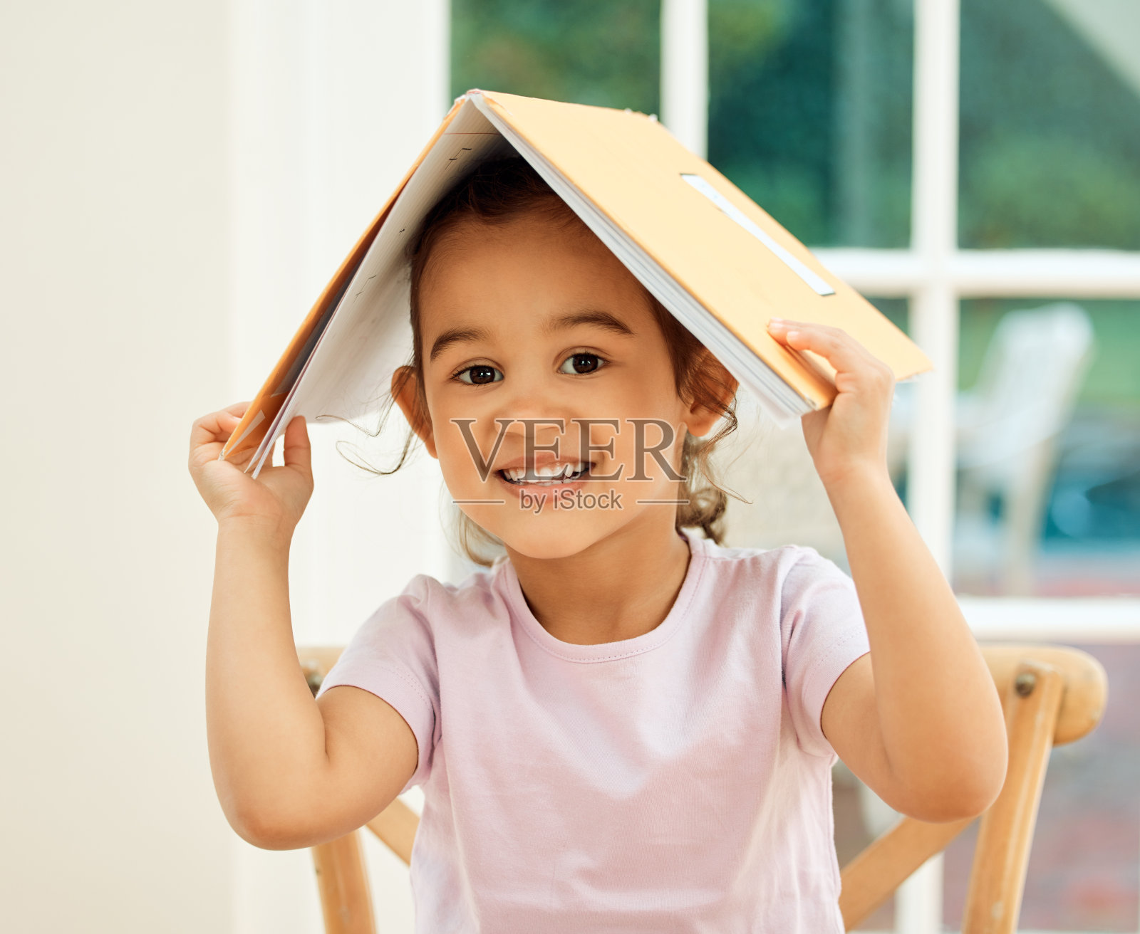 一个可爱的小女孩在做作业的时候摆弄她的课本照片摄影图片