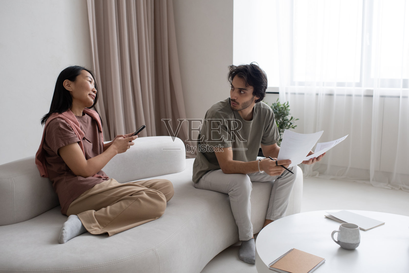 两个年轻的跨文化员工在家庭办公室讨论照片摄影图片