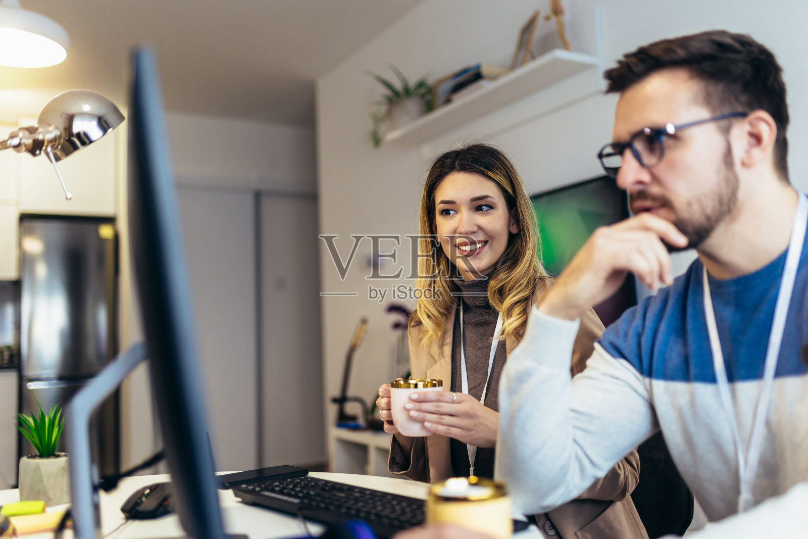 年轻夫妇，男人和女人，一起喝咖啡，在电脑上工作，坐在家里的桌子照片摄影图片