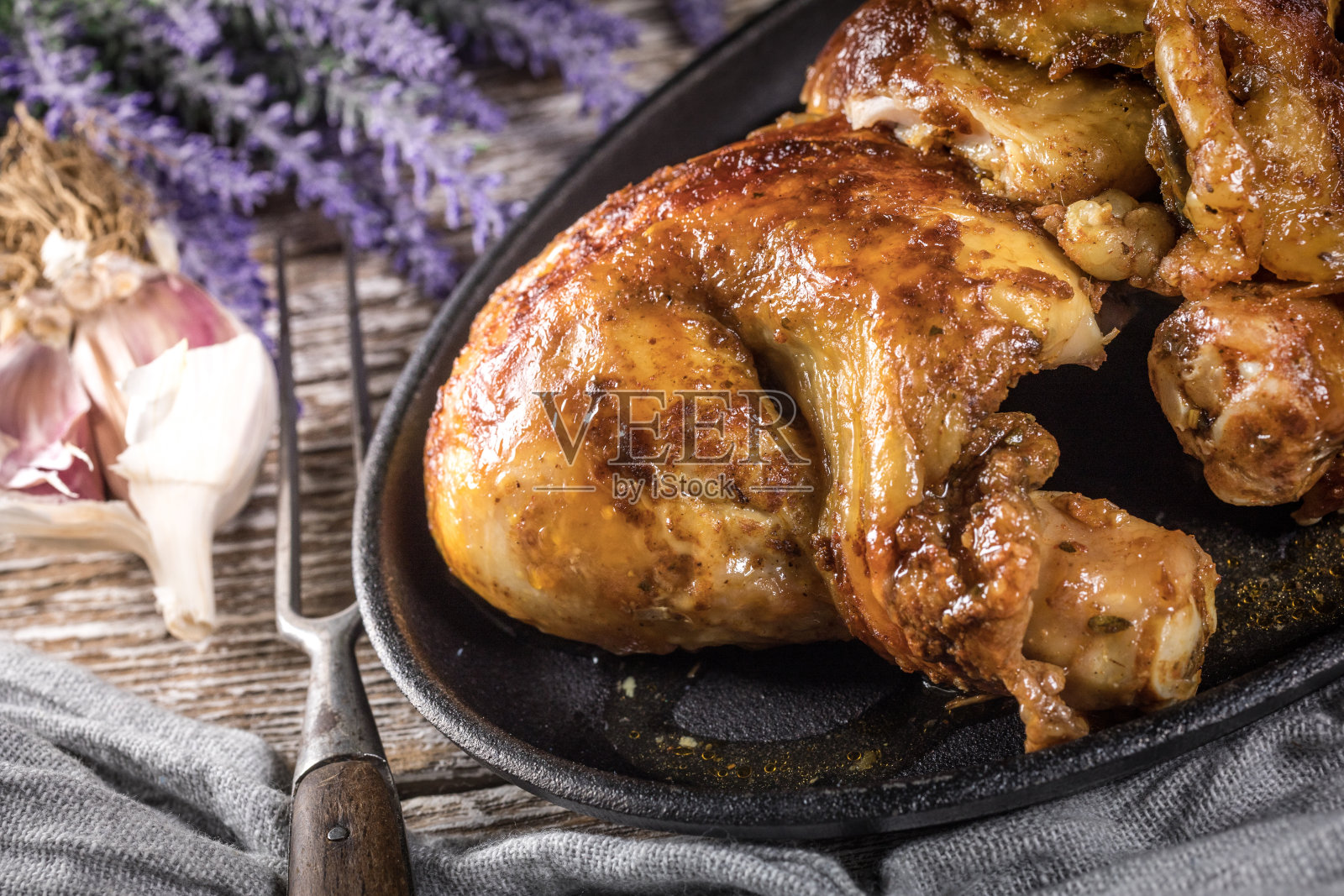 在铸铁煎锅里煎四分之一块炸鸡。照片摄影图片