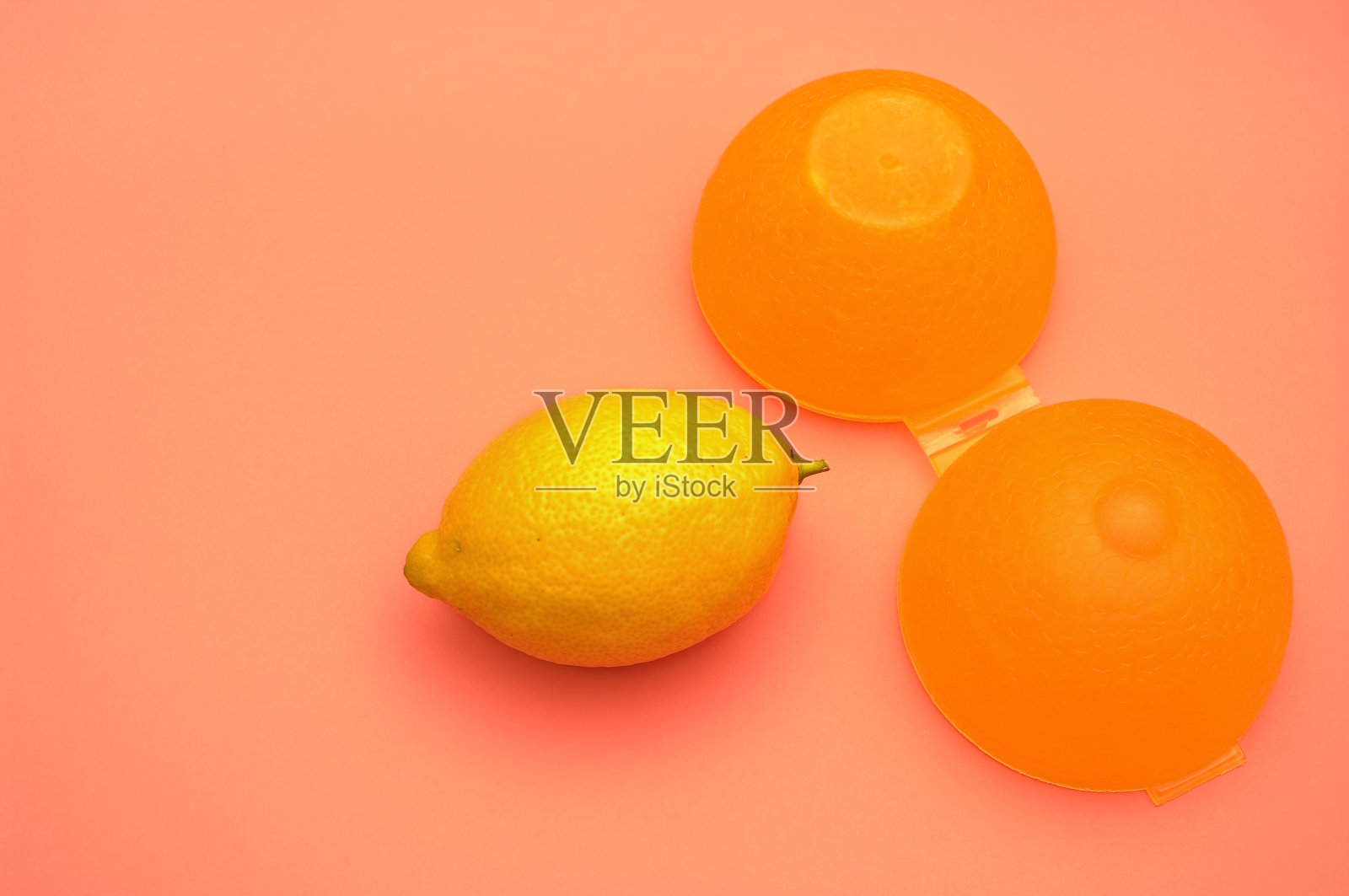 柠檬和它用来储存水果的黄色塑料容器。照片摄影图片