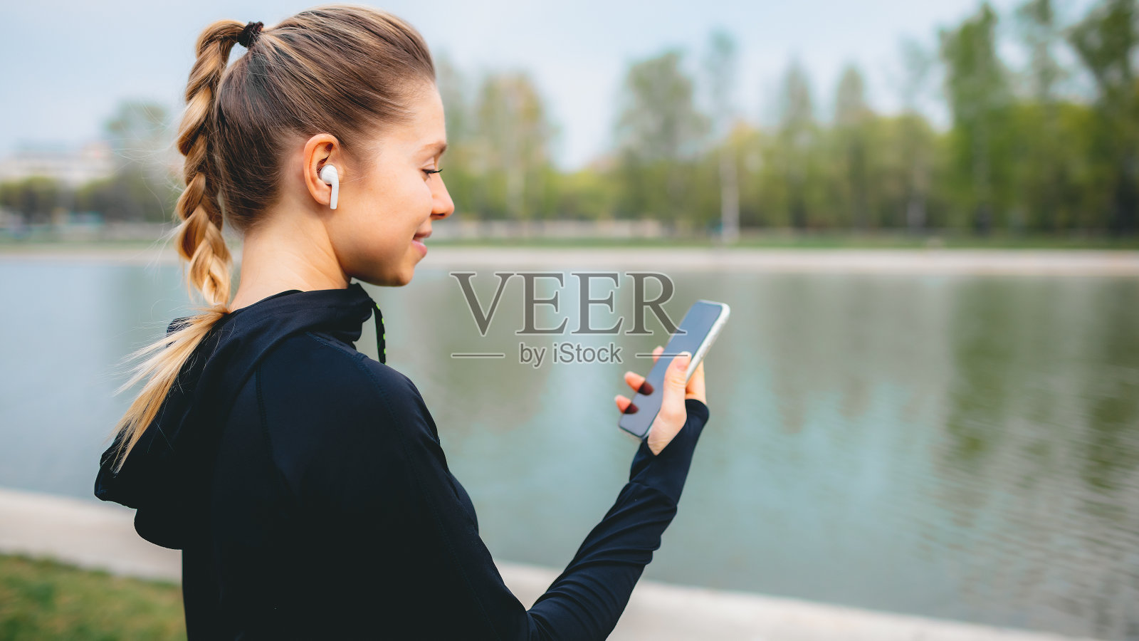 小女孩用手机和无线耳机在公园里做运动照片摄影图片