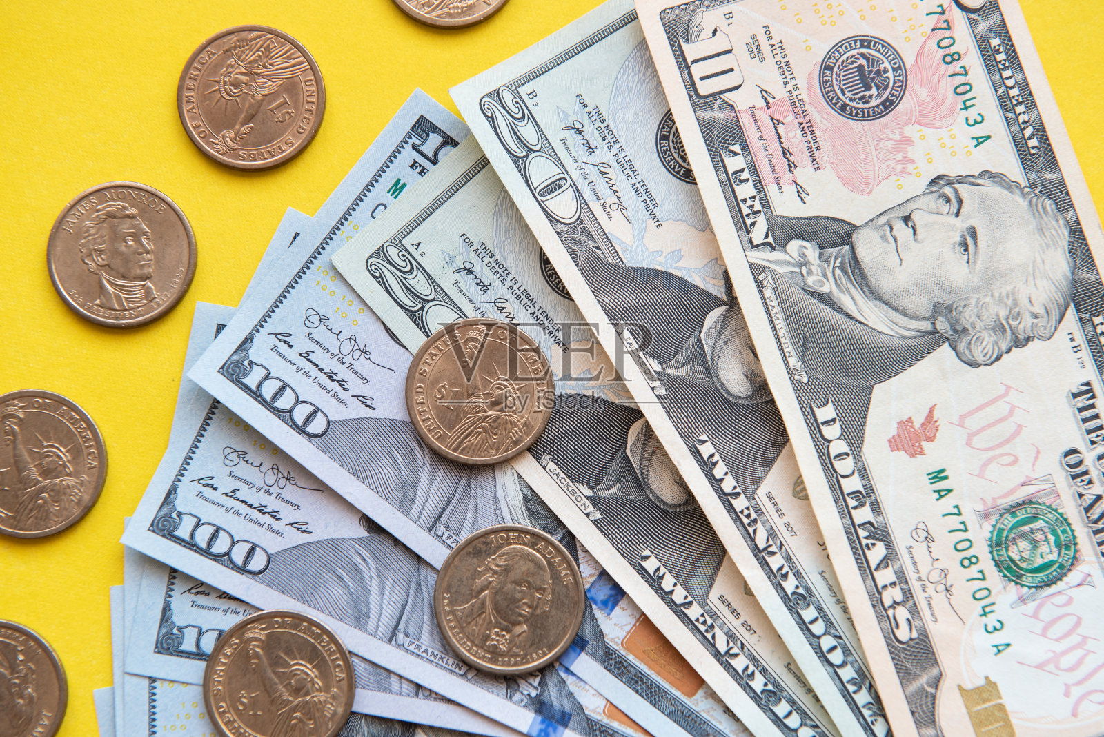 美元纸币和硬币。不同面额的美元纸币和硬币周围以黄色为背景照片摄影图片