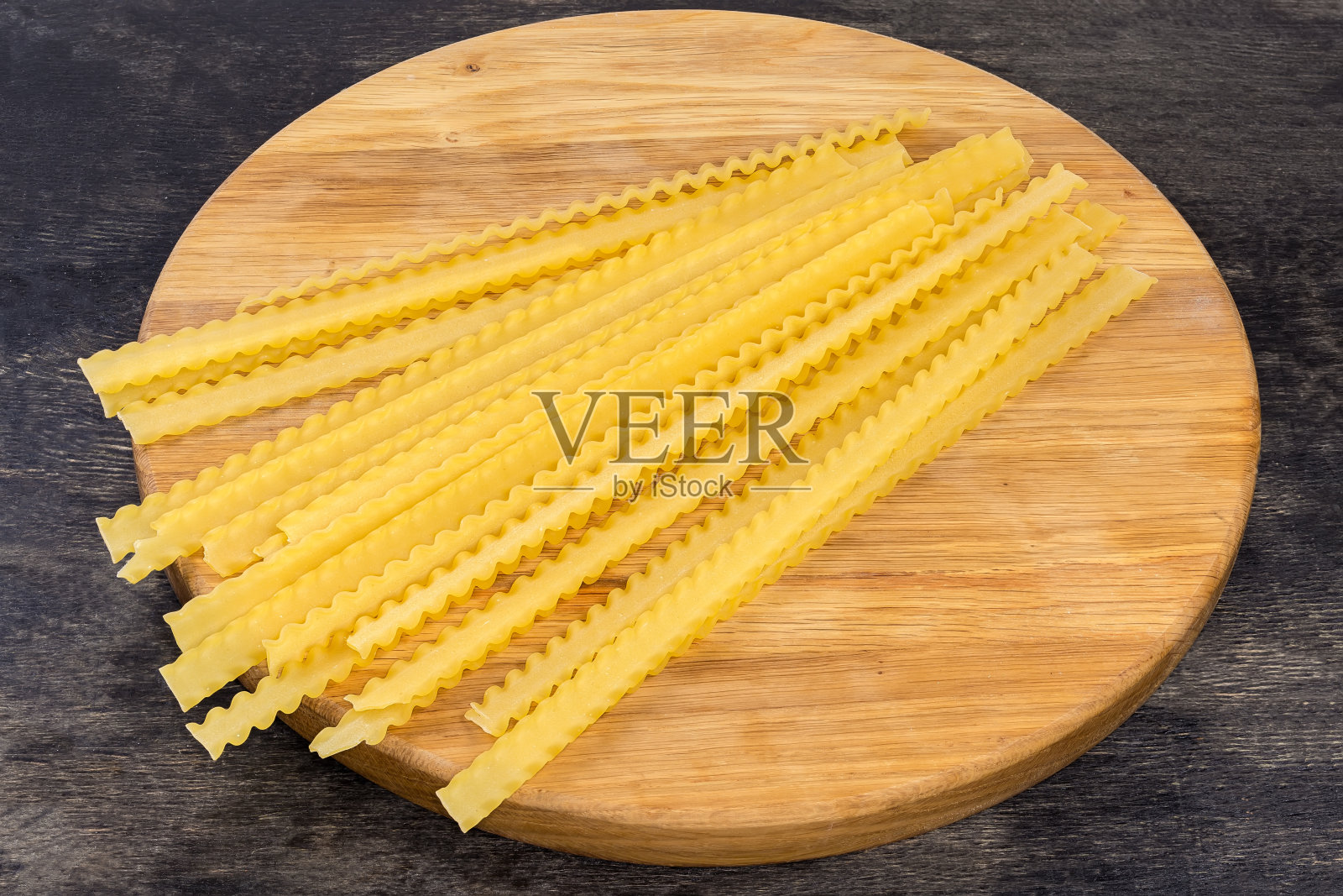 生的长马法尔丁意大利面在圆形木板上照片摄影图片