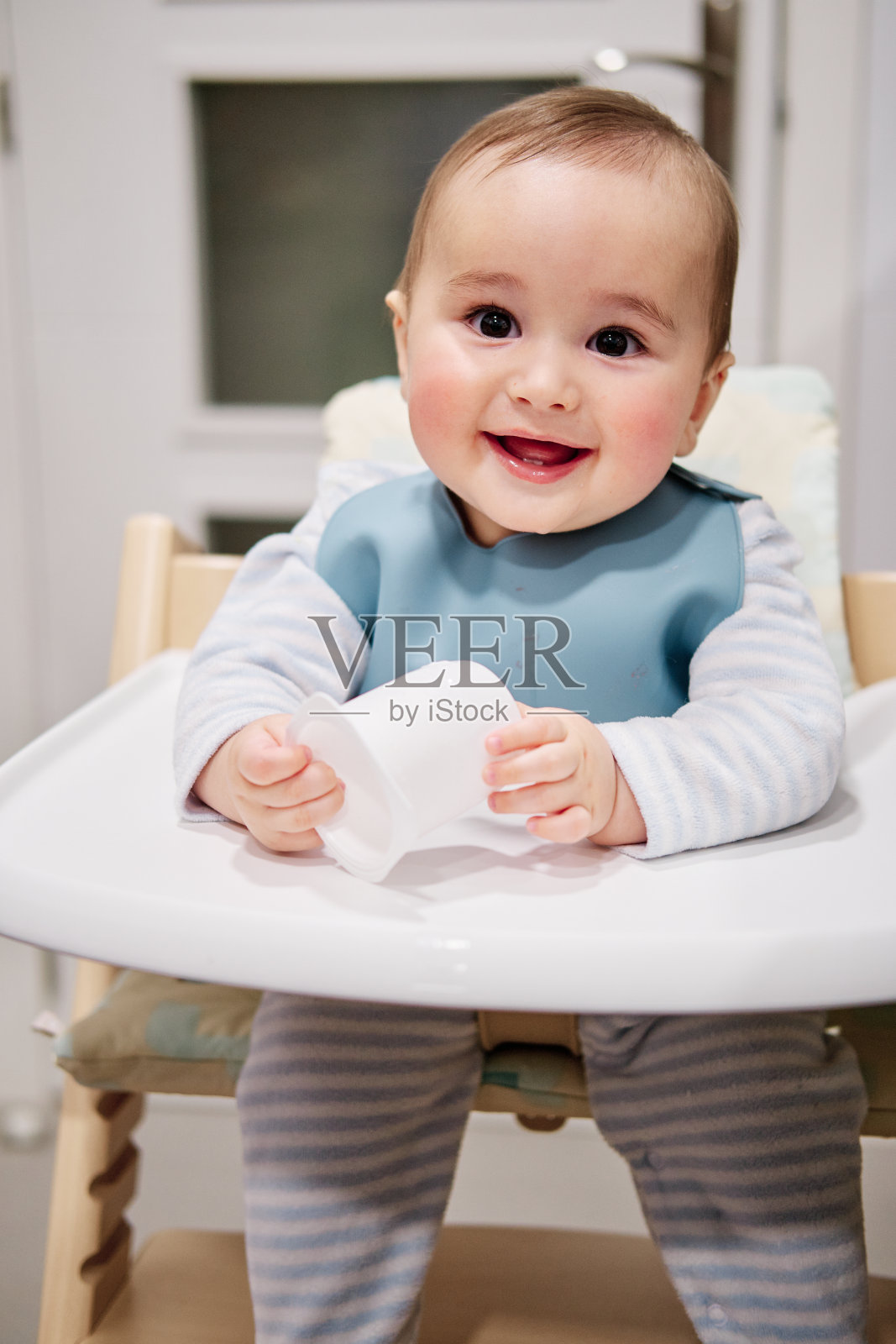 宝宝坐在高脚椅上玩酸奶盖照片摄影图片