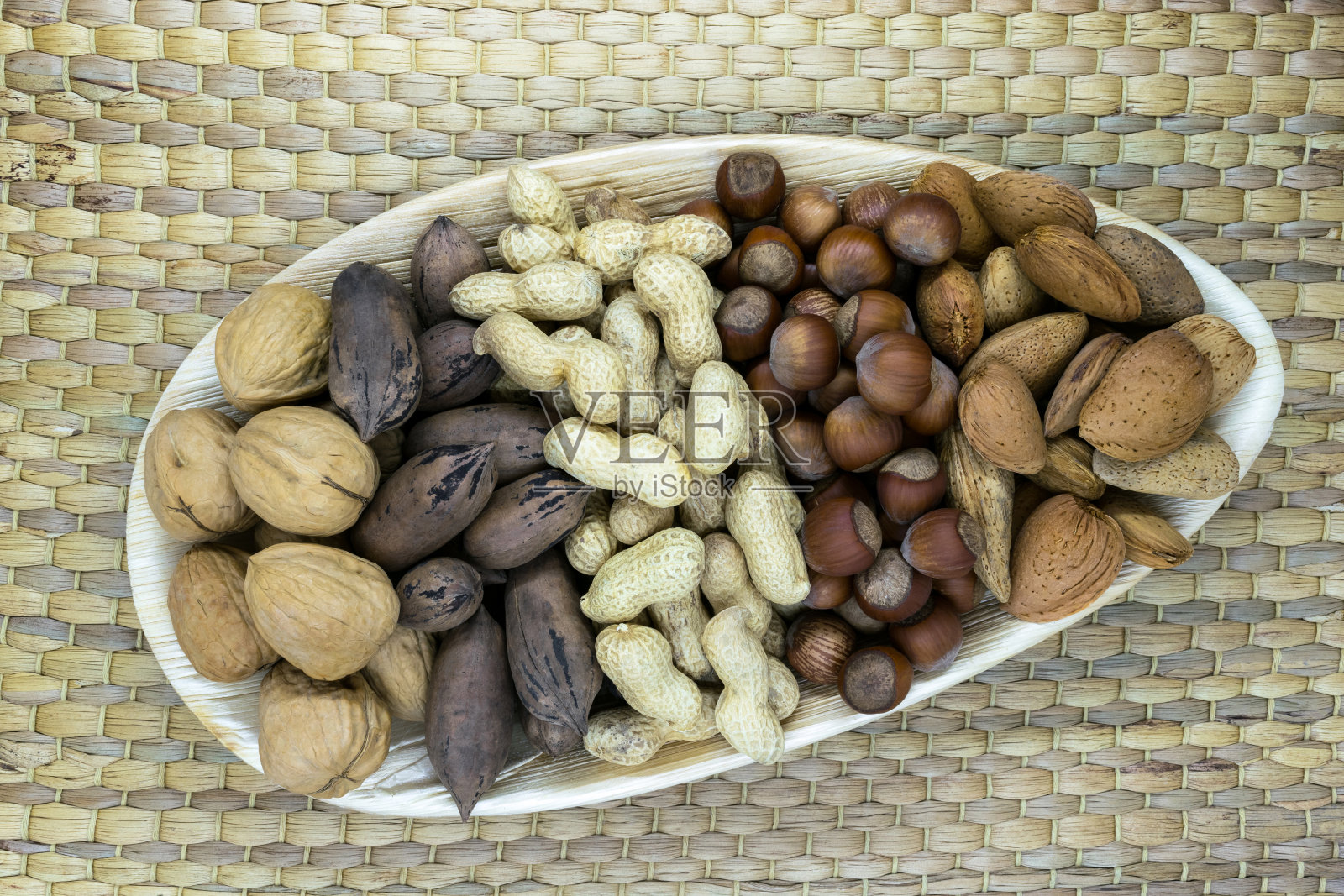 混合坚果。杏仁，山核桃，榛子，核桃，花生放置在生态自然的芭蕉叶板上，自然的竹tat与自由空间照片摄影图片