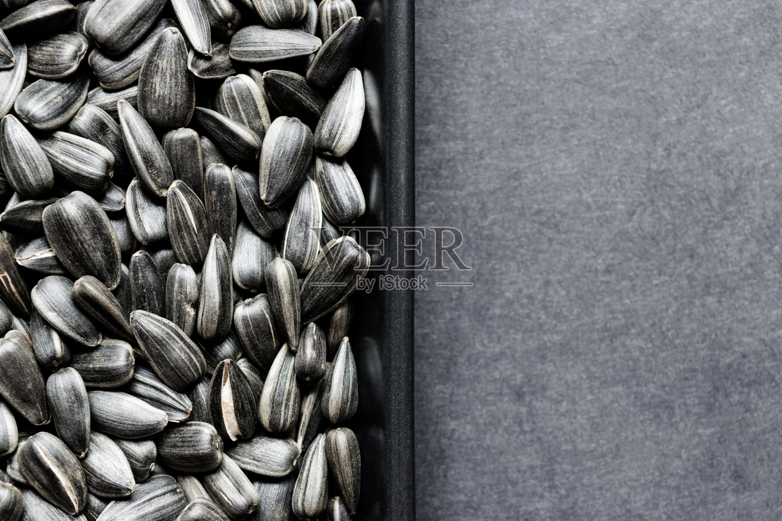 烤葵花籽在黑色的盘子上的背景表面与自由空间照片摄影图片
