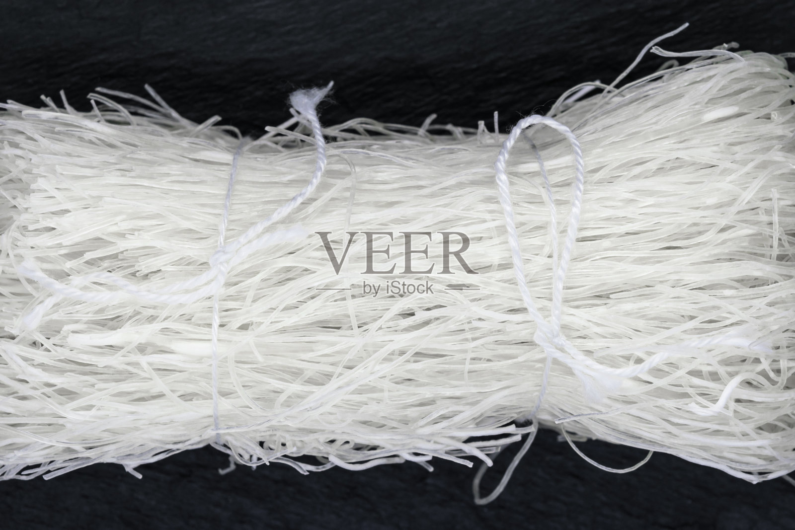 白色的米线用白色的绳子绑在黑色的石头底面上照片摄影图片