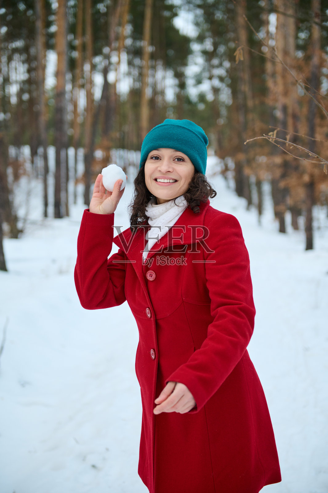 迷人的年轻女子玩着，扔着雪球，对着镜头露出欢快的露齿微笑。冬季雪地里的户外休闲活动照片摄影图片