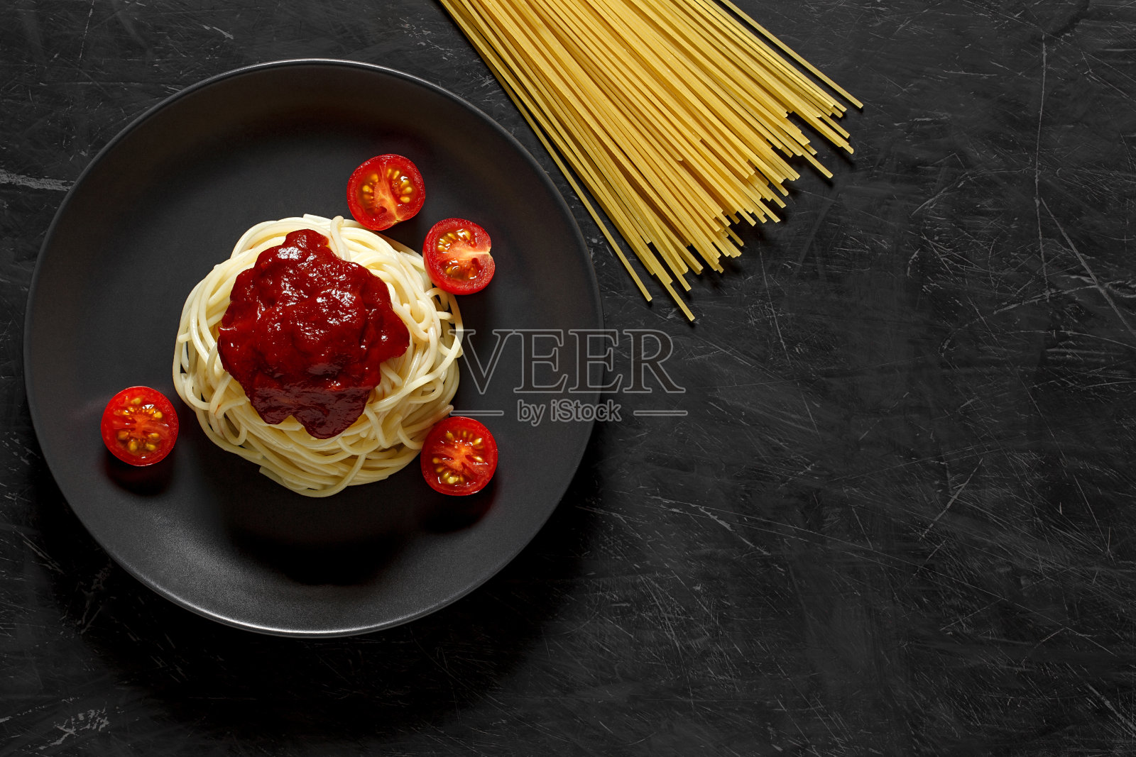 意大利面条意大利面煮番茄酱和樱桃番茄，在黑暗的背景，俯视图，复制文本的空间。照片摄影图片
