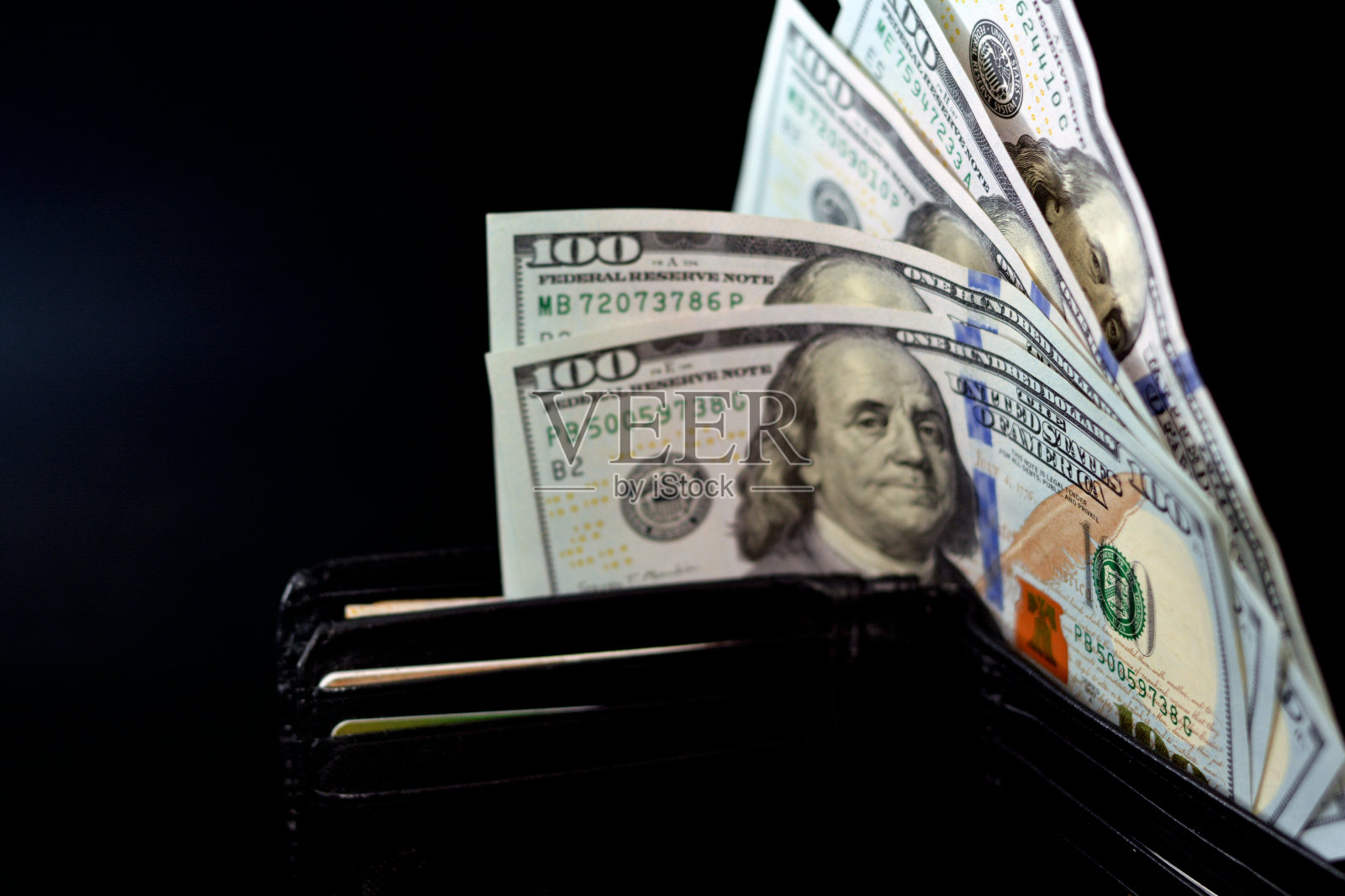 在黑色背景上孤立的一个黑色钱包里的美元钞票，100美元照片摄影图片