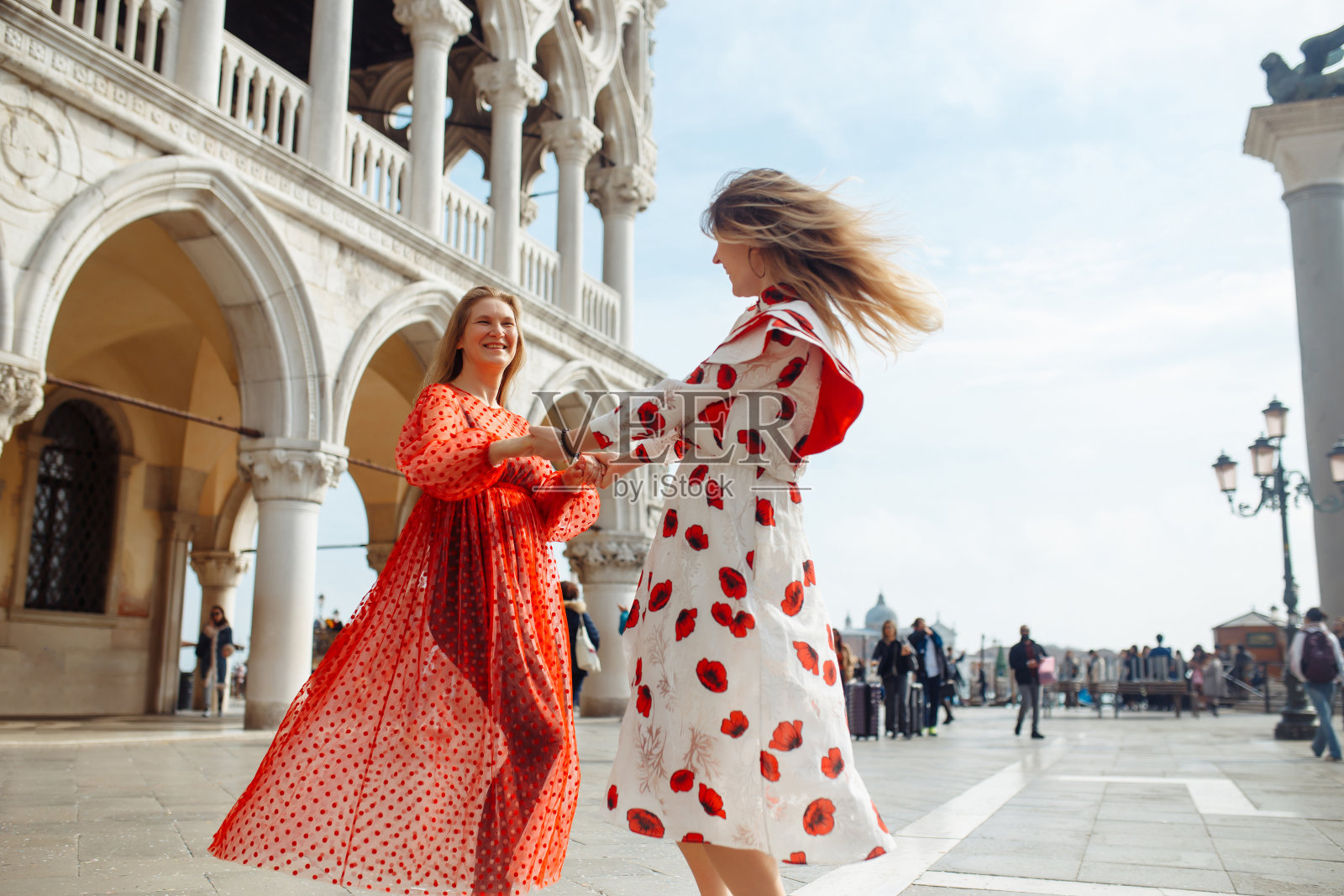 母女俩穿着时尚的衣服在威尼斯漫步。照片摄影图片