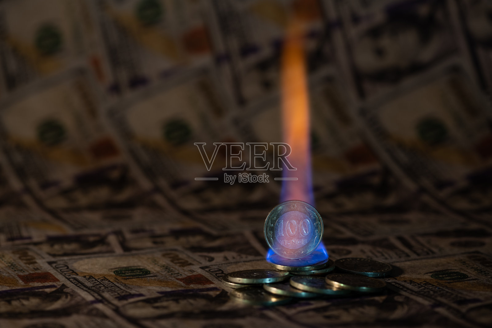 哈萨克100坚戈的硬币在美国纸币的背景下燃烧照片摄影图片