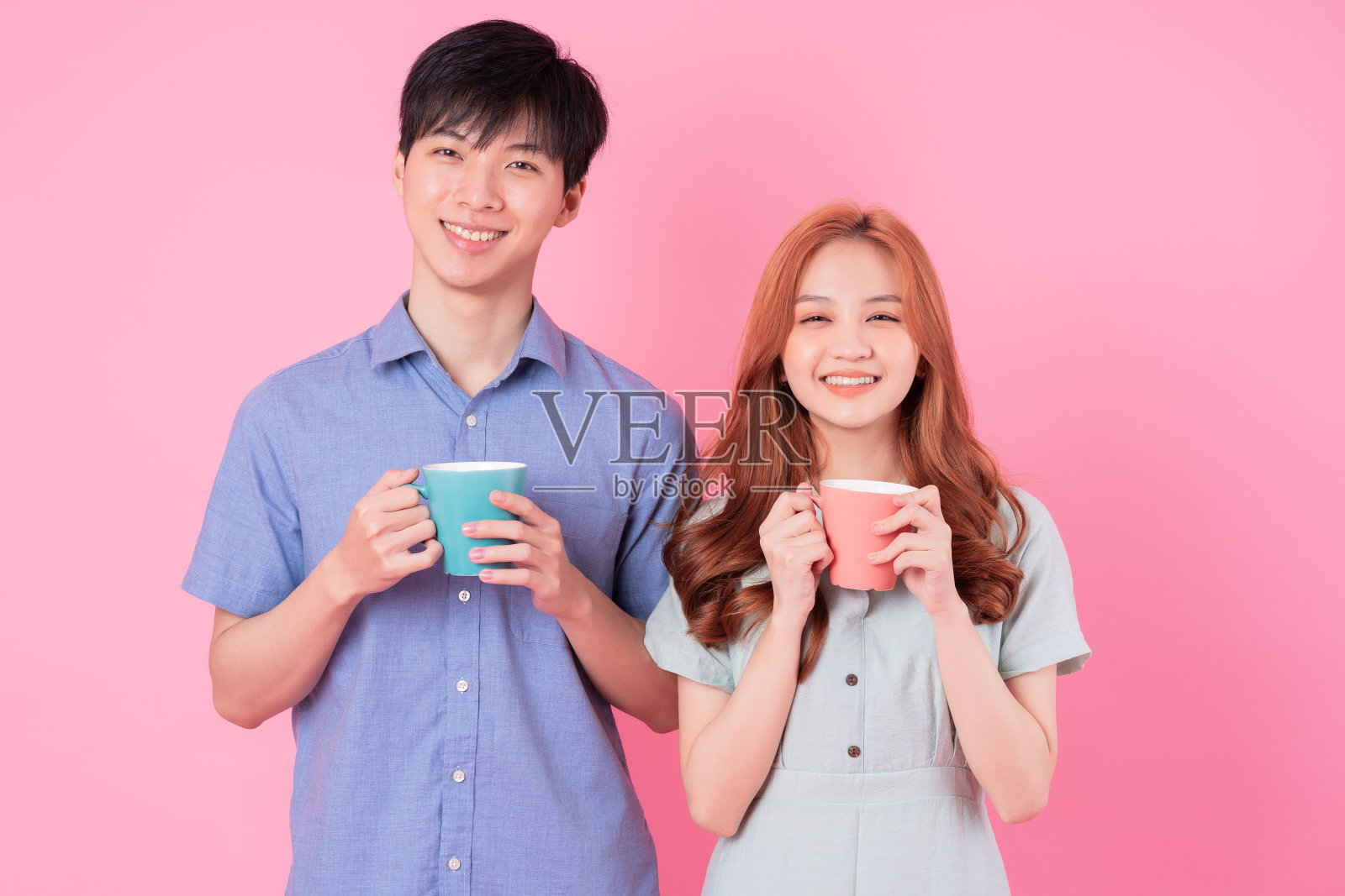 粉色背景下的亚洲年轻情侣喝茶照片摄影图片