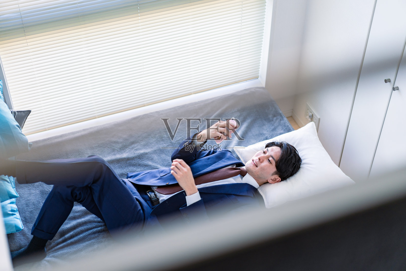 一位商人在床上使用智能手机照片摄影图片