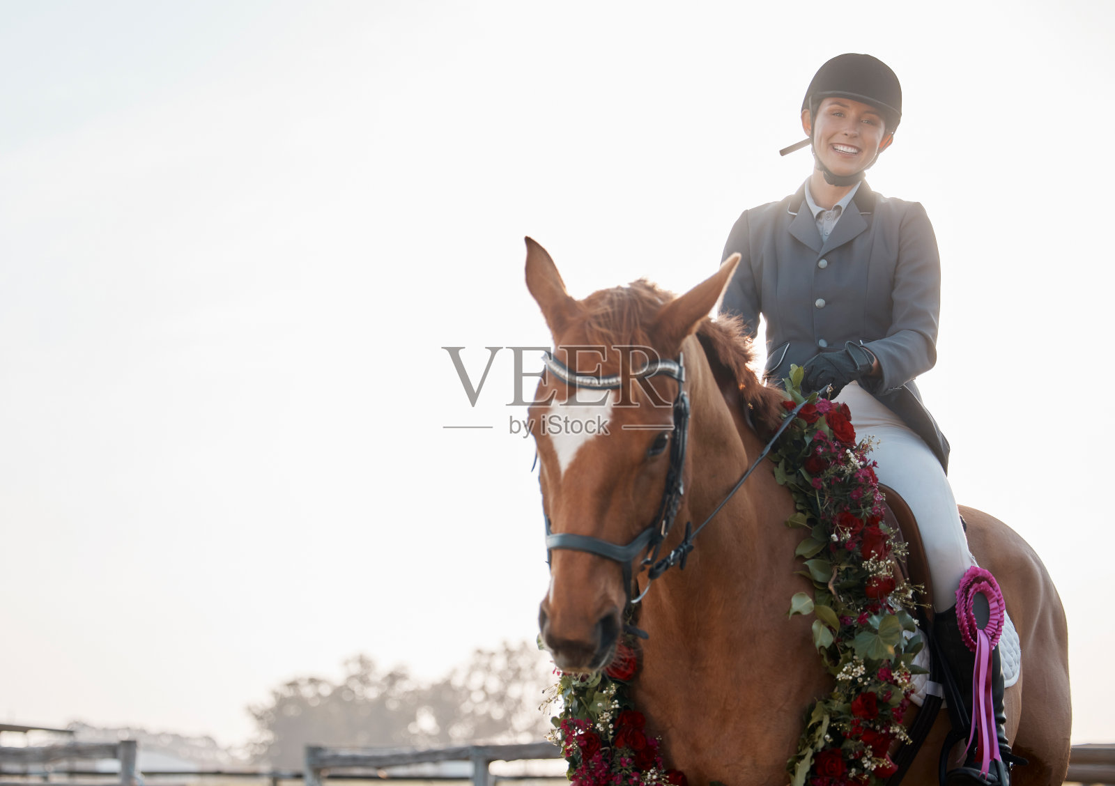 一名年轻的女骑师坐在她的花圈后赢得了一场比赛的镜头照片摄影图片