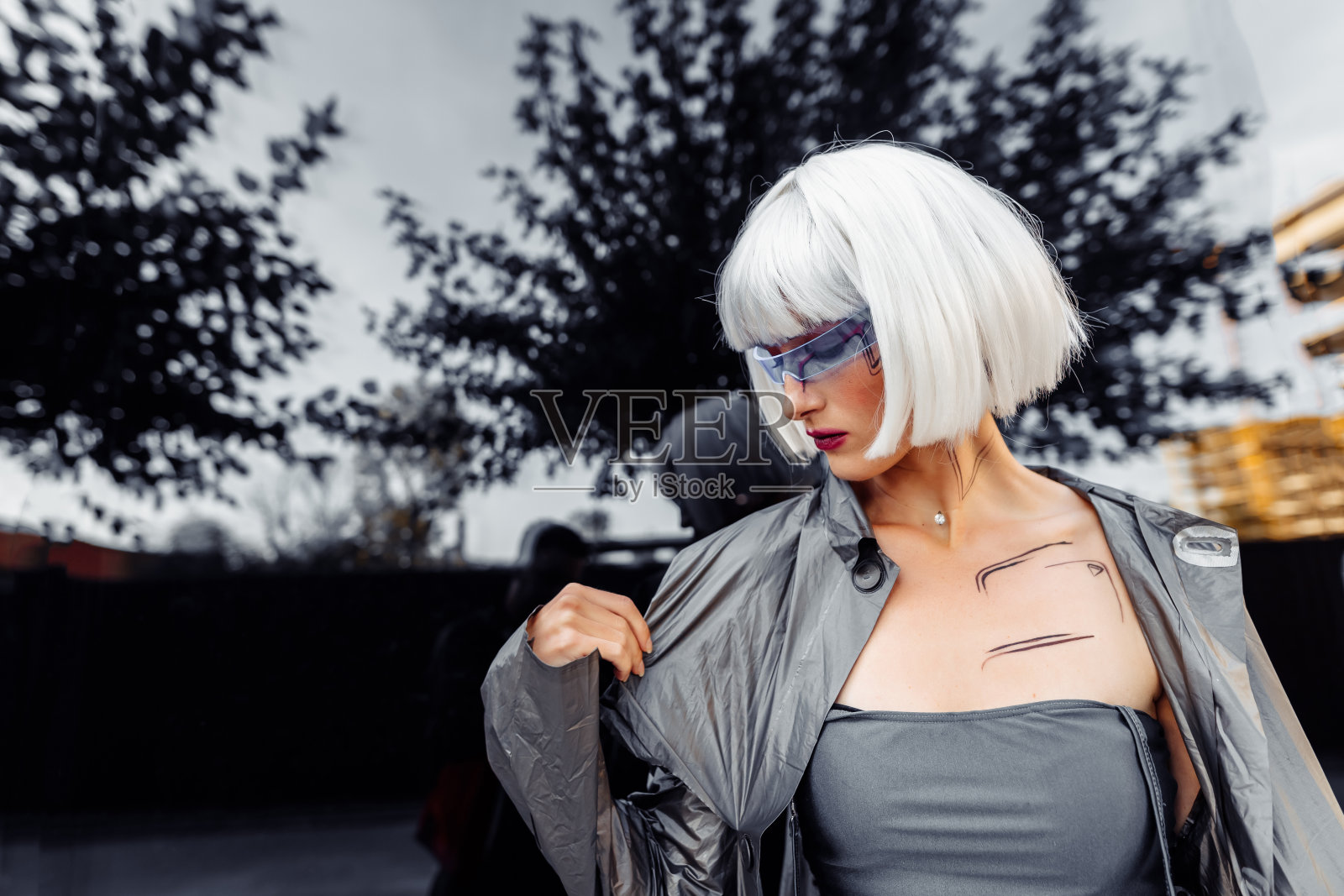 时尚的金发女郎穿着未来派的衣服，戴着眼镜在镜子的背景上照片摄影图片