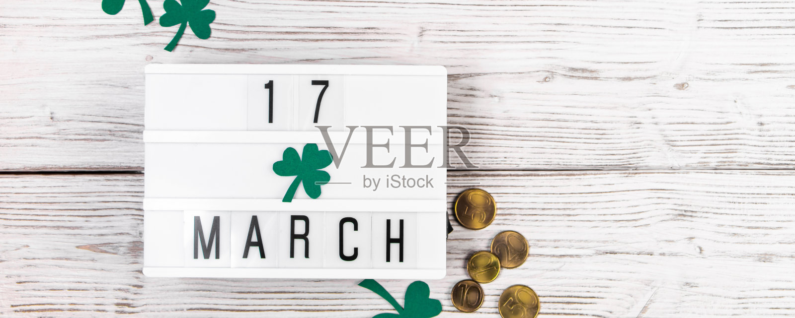 圣帕特里克节的Flatlay。金币和三叶草叶子在白色的木质背景上。爱尔兰节日快乐，象征着好运。照片摄影图片