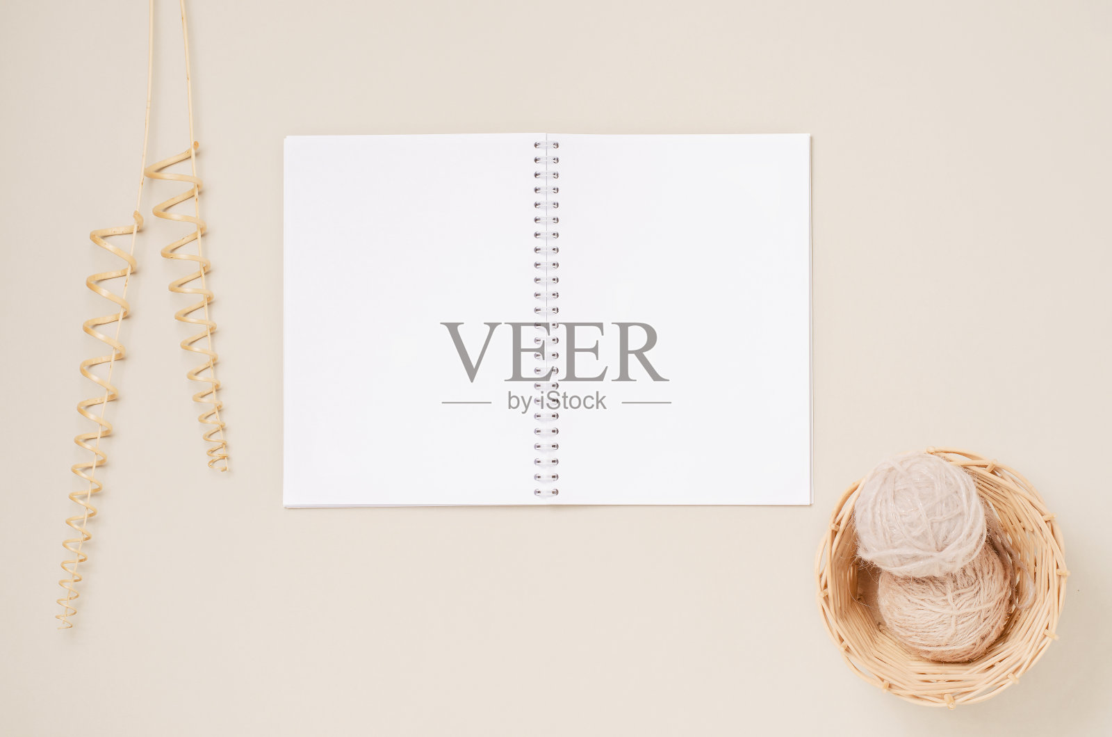 一本白色的笔记本，柳条篮里的线和一根装饰的干藤树枝。米色背景。副本的空间。照片摄影图片